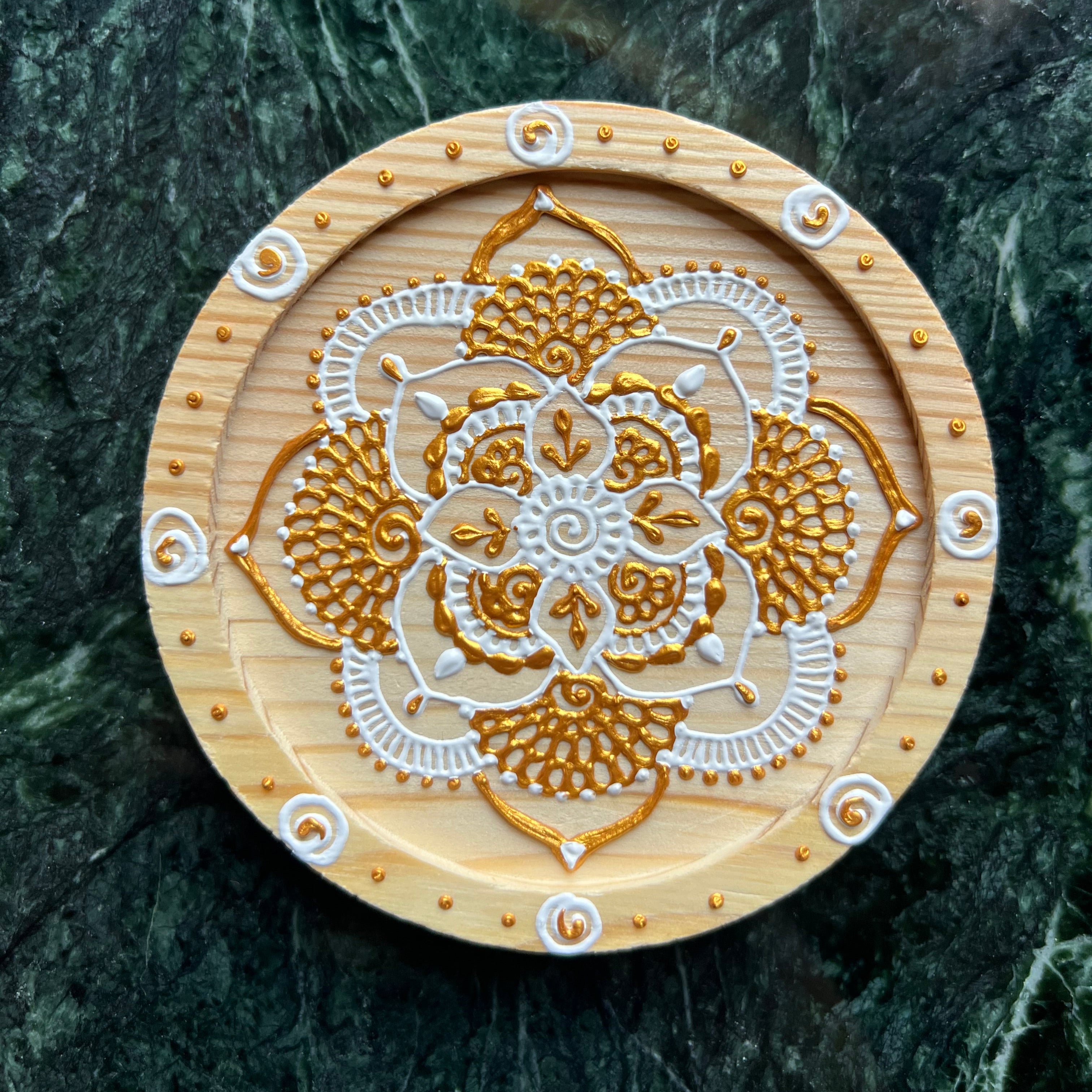 Hand-painted wooden coaster featuring henna mandala design, top view